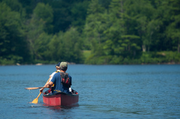 Bright red kayak with two persons rowing, on lake