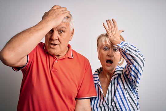Senior beautiful couple standing together over isolated white background surprised with hand on head for mistake, remember error. Forgot, bad memory concept.