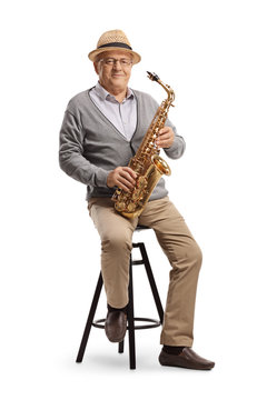 Elderly man sitting on a chair and holding a saxophone
