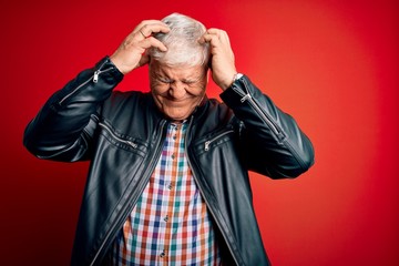 Senior handsome hoary man wearing casual shirt and jacket over isolated red background suffering from headache desperate and stressed because pain and migraine. Hands on head.