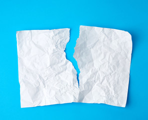crumpled white sheet of paper torn in two on a blue background