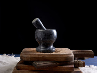 Fototapeta na wymiar black stone mortar with pestle for grinding spices and herbs on a brown wooden board