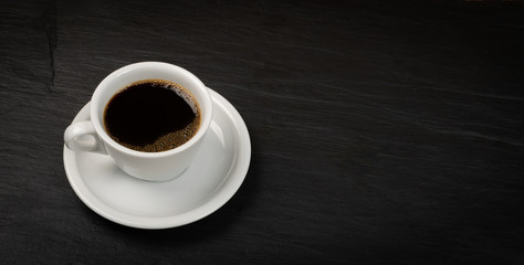 Hot coffee cup on black stone background with copyspace