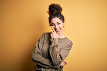 Fototapeta na wymiar Young beautiful brunette woman with curly hair and piercing wearing casual dress looking confident at the camera smiling with crossed arms and hand raised on chin. Thinking positive.