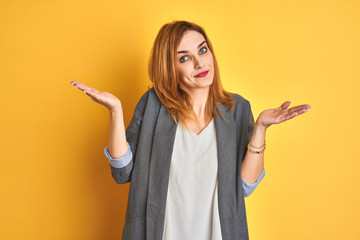 Redhead caucasian business woman over yellow isolated background looking to the side with arms crossed convinced and confident