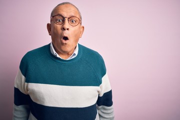 Senior handsome man wearing casual sweater and glasses over isolated pink background afraid and shocked with surprise expression, fear and excited face.