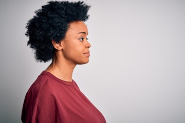 Fototapeta na wymiar Young beautiful African American afro woman with curly hair wearing casual t-shirt standing looking to side, relax profile pose with natural face with confident smile.