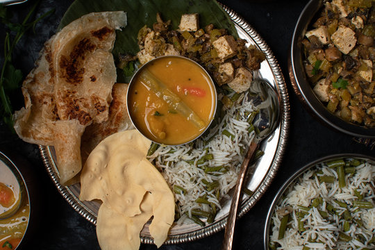 Indian vegan thali meal with rice pilaf, paratha, dal, mushroom tofu curry
