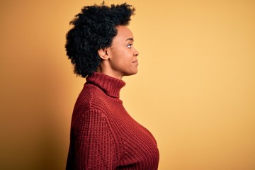 Young beautiful African American afro woman with curly hair wearing casual turtleneck sweater...