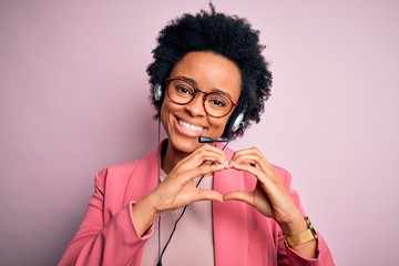 Young African American call center operator woman with curly hair using headset smiling in love...