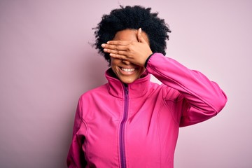Fototapeta na wymiar Young African American afro sportswoman with curly hair wearing sportswear doin sport smiling and laughing with hand on face covering eyes for surprise. Blind concept.