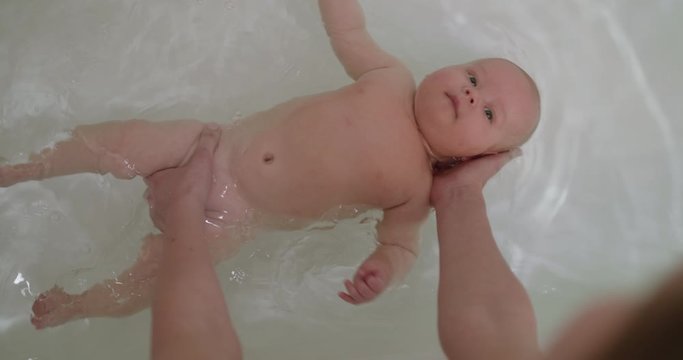 Top view of funny newborn baby swimming during bathing