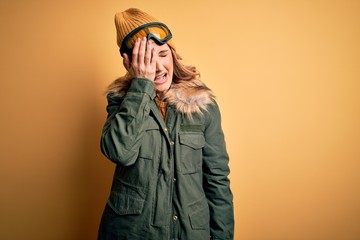 Middle age beautiful blonde skier woman wearing snow sportwear and ski goggles Yawning tired covering half face, eye and mouth with hand. Face hurts in pain.