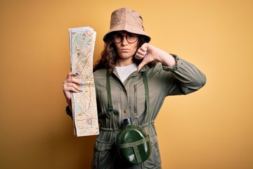 Beautiful tourist woman on vacation wearing explorer hat and water canteen holding city map with...