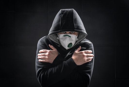 The concept of epidemic coronavirus pandemic quarantine. Man in hoodie on a black with medical mask