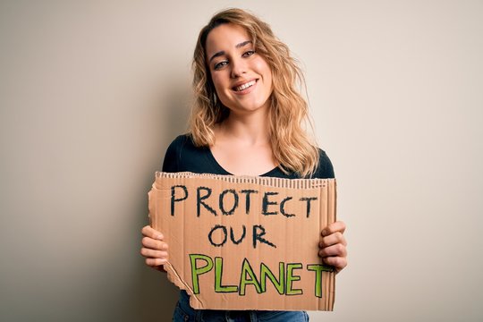 Young activist woman asking for environment holding banner with protect planet message with a happy face standing and smiling with a confident smile showing teeth