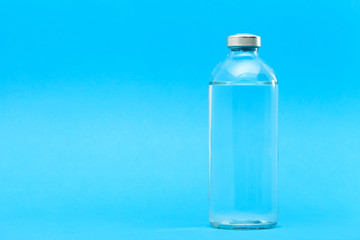 glass bottle with liquid for vaccination of patients for the treatment of health on a blue background with copy space.