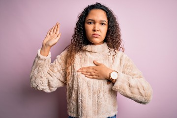Young beautiful woman with curly hair wearing casual sweater standing over pink background Swearing...