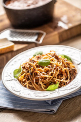 Italian pasta spaghetti bolognese served on white plate with parmesan cheese and basil