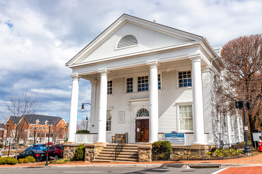 City of Fairfax, USA - March 10, 2020: Old town hall colonial architecture with sign for Huddleson Memorial public library, community events in downtown at University drive in Fairfax county, Virginia