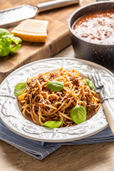Italian pasta spaghetti bolognese served on white plate with parmesan cheese and basil