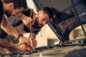 Two mechanics in uniform are working in auto service