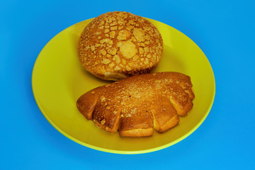 Freshly baked bun with a crispy crust close-up on a blue background.