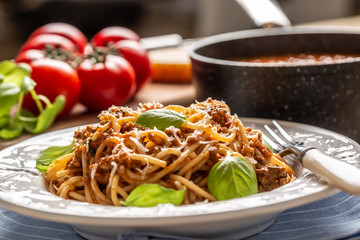 Italian pasta spaghetti bolognese served on white plate with parmesan cheese and basil