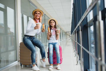 Obraz premium mom with her daughter at airport terminal with suitcases eating fast food