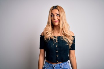 Young beautiful blonde woman wearing casual t-shirt standing over isolated white background smiling looking to the side and staring away thinking.