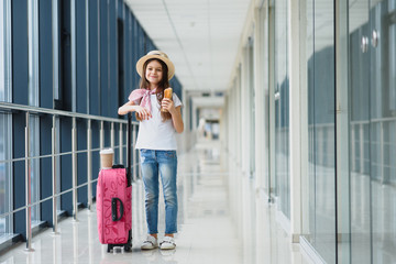 tourism, vacation, childhood and transportation concept - smiling little girl with travel bag, ticket and passport over airport background