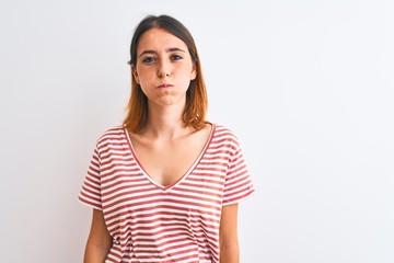 Fototapeta premium Beautiful redhead woman wearing casual striped red t-shirt over isolated background puffing cheeks with funny face. Mouth inflated with air, crazy expression.