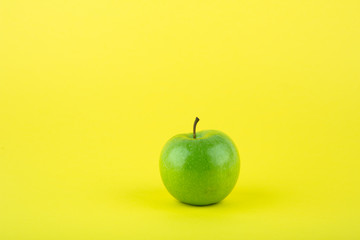 green apple on yellow background with copy space