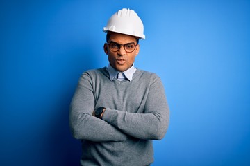 Young handsome african american engineer man with dreadlocks wearing safety helmet skeptic and nervous, disapproving expression on face with crossed arms. Negative person.