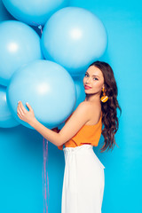 Fototapeta premium beautiful stylish girl smiling at camera while holding big festive balloons on blue background