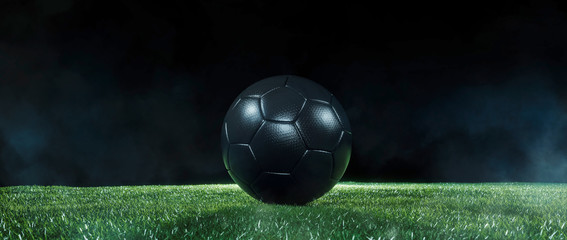 Black Football on an illuminated empty sports field at night.