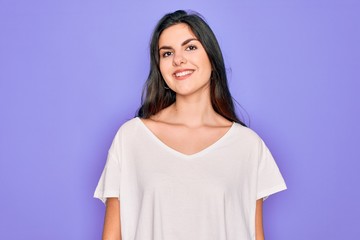 Fototapeta premium Young beautiful brunette woman wearing casual white t-shirt over purple background with a happy and cool smile on face. Lucky person.