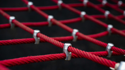 Cord equipment,string furniture,rope facilities,climbing tread. Twisted knot. Jungle gym. Made of ropes. Red ropes background. red strings, red cords. Rope plaything. Connection,union,joint,coupling.