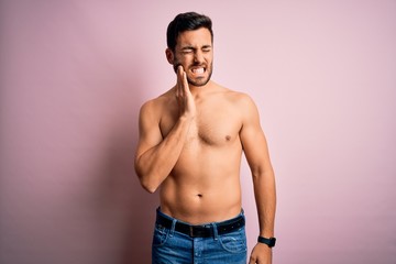 Young handsome strong man with beard shirtless standing over isolated pink background touching mouth with hand with painful expression because of toothache or dental illness on teeth. Dentist