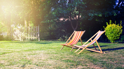 Two Chilean lounge chairs installed in the garden on the lawn facing the sun.