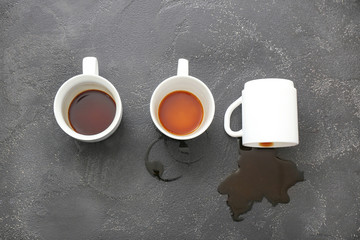 Cups and spilled coffee on grey background