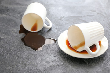 Overturned cups of coffee on grey background