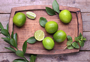 Fresh limes and board on wooden background