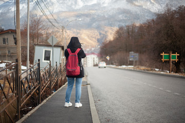 A girl stands on a road in the mountains.