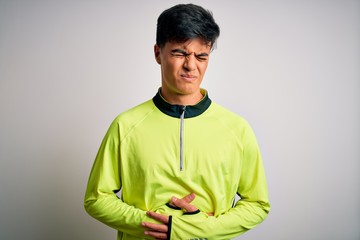 Young handsome sportsman doing sport wearing sportswear over isolated white background with hand on stomach because indigestion, painful illness feeling unwell. Ache concept.