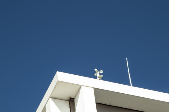 small pinwheel on a roof, white building, blue sky