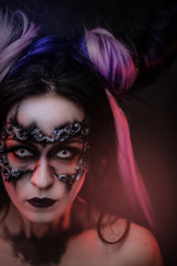 Fototapeta premium Close up vertical photo of a mystic young girl in a magic creature cosplay, wearing dark banshee make-up and violet horns, looking spooky straight to camera