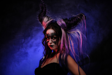 Portrait photo of a mystic young girl in a magic creature cosplay, wearing dark banshee make-up and violet horns, looking scary surrounded by smoke