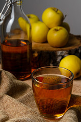 Full bottle of cider with basket of yellow apples.