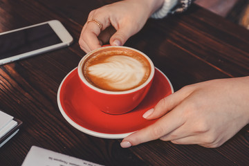 Woman drinking tasty cappuccino at wooden table